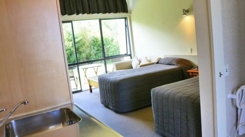 a hotel room with a bed and a sink and a window at Sunset Motel in Fox Glacier