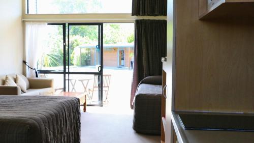 a hotel room with a bed and a sliding glass door at Sunset Motel in Fox Glacier