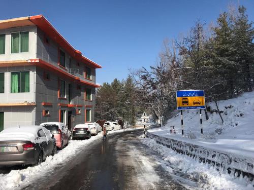 eine schneebedeckte Straße mit Autos neben einem Gebäude in der Unterkunft Green Valley Apartments in Bhurban