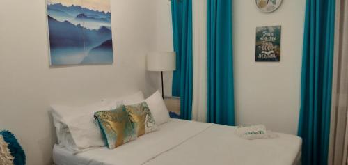 a bedroom with a white bed with blue curtains at Retreat Haven in La Bella Tagaytay in Tagaytay