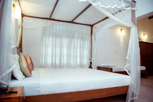 a bedroom with a white bed with a canopy at Prince Beach Hotel Bentota in Bentota