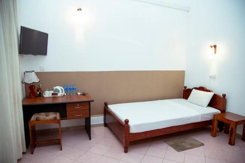 a small bedroom with a bed and a desk at Prince Beach Hotel Bentota in Bentota