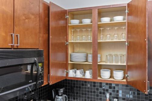 a kitchen with wooden cabinets with plates and cups at Trifecta 10 Min Walk to Epicentre Superhost in Charlotte