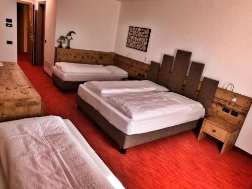 a bedroom with two beds and a red floor at Hotel Cristallo in Canazei