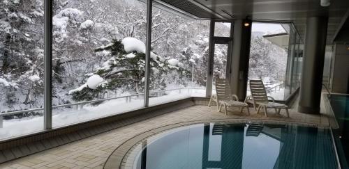 a swimming pool in a house with snow on the windows at Yoshikawaya in Fukushima