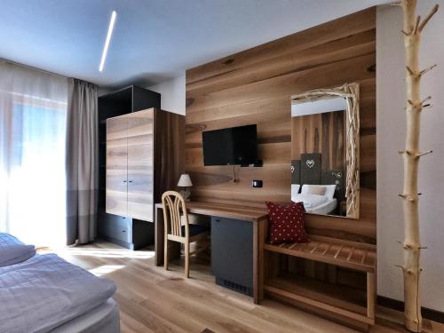 een slaapkamer met een bureau, een bed en een spiegel bij Hotel Cristallo in Canazei