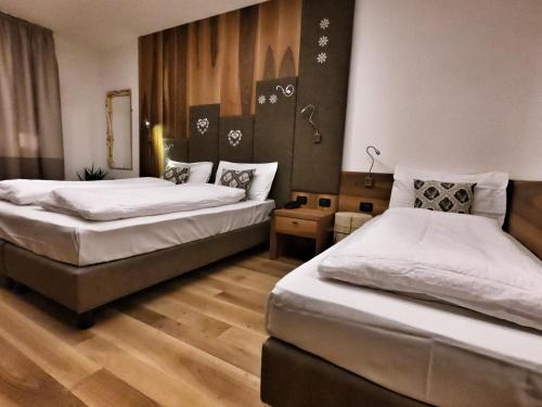 two beds in a room with wooden floors at Hotel Cristallo in Canazei