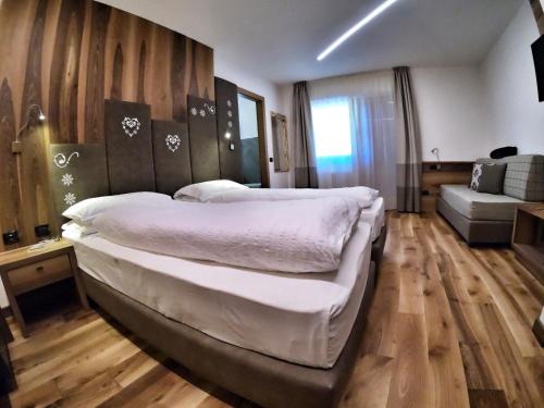 a large bedroom with two beds and a couch at Hotel Cristallo in Canazei