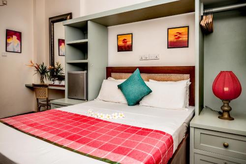 een slaapkamer met een bed met een rode en groene deken bij Small House Boutique Guest House in Galle