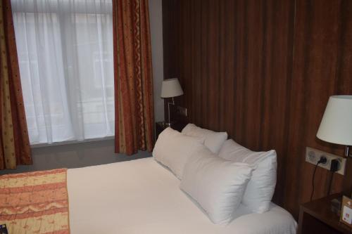 a bedroom with a bed with white pillows and a window at Metropol Hotel in Calais