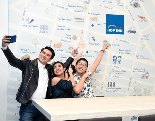 a group of people sitting at a table with their hands in the air at Hop Inn Hotel Tomas Morato Quezon City in Manila