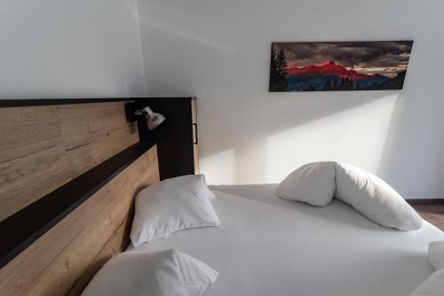 a bed with white sheets and pillows in a room at A CASA Rubin Chalet & Studio Resort in Sölden