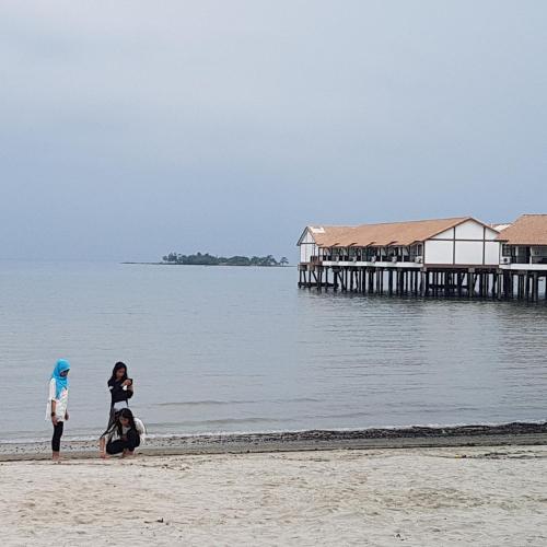 two people standing on the beach near the water at Tokido Private Water Chalet PD in Port Dickson