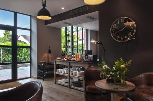 un restaurante con un reloj en la pared y una mesa en Hotel Les Terres Blanches, en Chatou