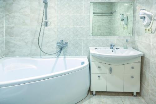 een badkamer met een bad, een wastafel en een douche bij Art-Hotel Centralnyi in Kostroma