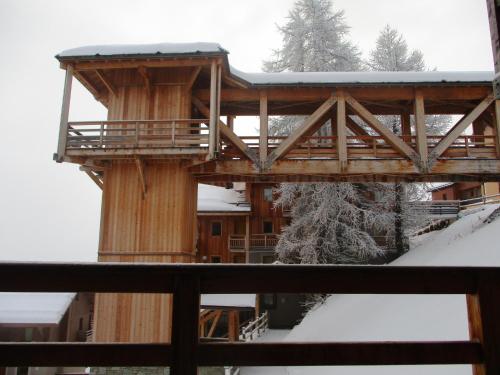 a ski lodge with a deck in the snow at Duplex Familial à Vars, Chalets des Rennes in Vars
