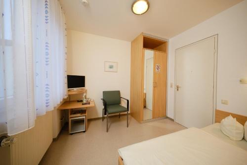 1 dormitorio con escritorio, 1 cama y 1 silla en Gästehaus Schumm en Murrhardt