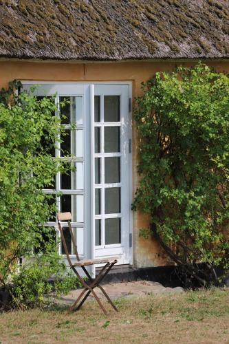 a chair sitting outside of a house with a door at Bakkehuset Countryhouse in Skovby