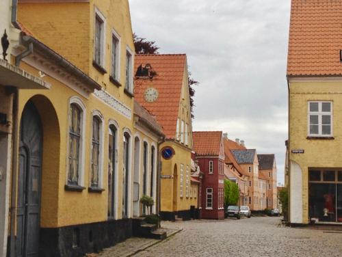 an empty street in a town with yellow buildings at Bakkehuset Countryhouse in Skovby