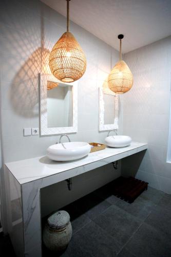 a bathroom with two sinks and two mirrors at Vanilla Suite Jimbaran in Jimbaran