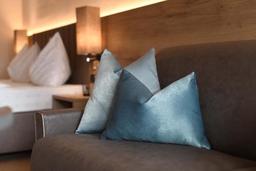 a couch with blue pillows in a hotel room at Hotel Das Stachelburg in Parcines