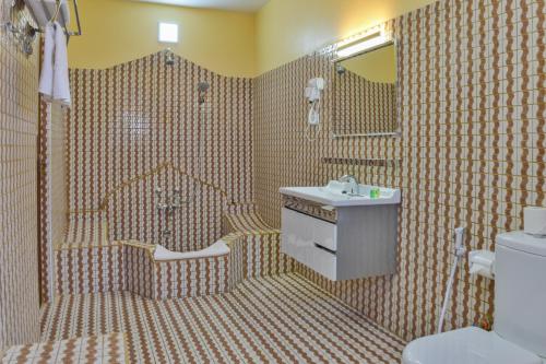 a bathroom with a sink and a toilet and a mirror at Tembo B&B Apartments in Zanzibar City