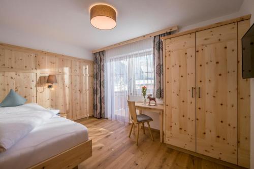 1 dormitorio con cama, escritorio y ventana en Appartementhaus Adlerblick en Mayrhofen