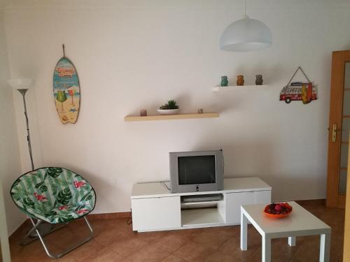 a living room with a tv and a chair at São Martinho do Porto in São Martinho do Porto