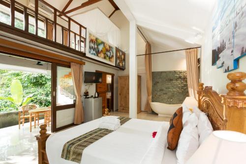 a bedroom with a large bed and a tub at Rahayu Suites Monkey Forest Ubud in Ubud