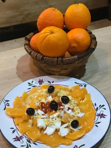 a plate of food on a table with a bowl of oranges at Casa Rural Valle del Arrago in Robledillo de Gata