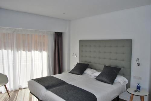 sypialnia z dużym łóżkiem i dużym oknem w obiekcie Estudiotel Alicante w Alicante