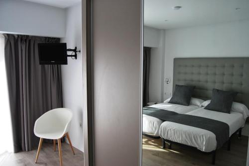 a bedroom with a bed and a chair and a mirror at Estudiotel Alicante in Alicante