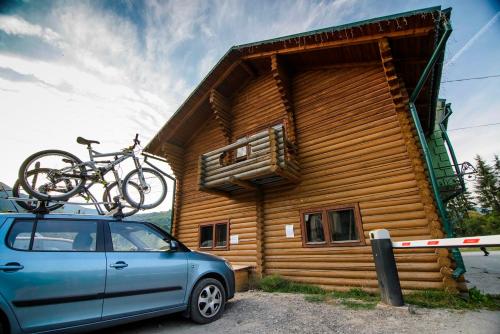 a car parked in front of a log cabin with a bike on the roof at Хостел Васкул in Kvasy
