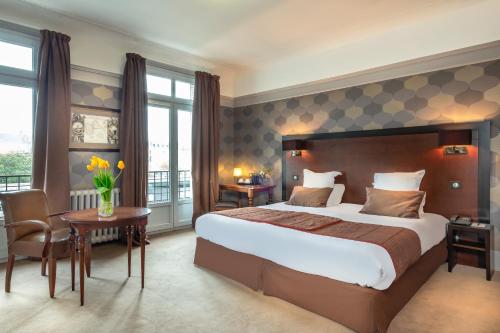 Cette chambre comprend un grand lit et une table. dans l'établissement Le Grand Hotel, à Tours