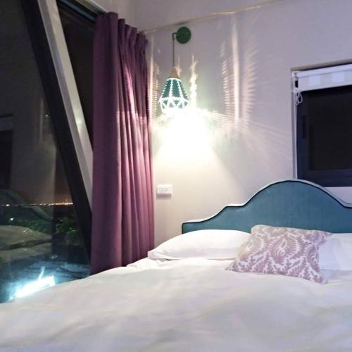 a bedroom with a bed with a lamp and a window at Top Sunlight Inn in Xiaoliuqiu