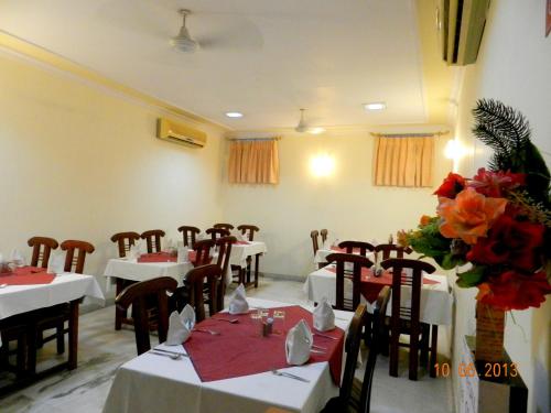 un comedor con mesas blancas, sillas y flores en Hotel Tara Palace, Chandni Chowk en Nueva Delhi