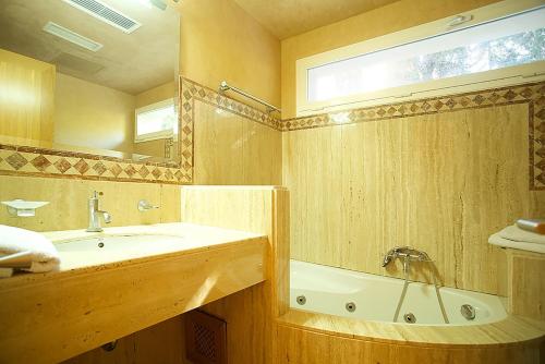 een badkamer met een wastafel, een bad en een spiegel bij Villa Narcis in Alcudia