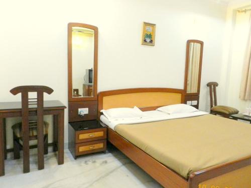 a bedroom with a bed and a table and a mirror at Hotel Tara Palace, Chandni Chowk in New Delhi