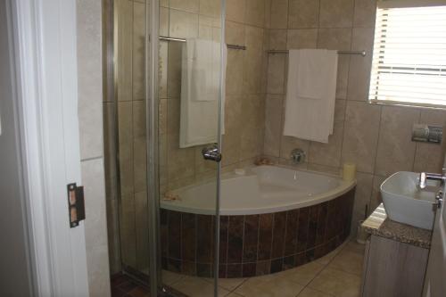 a bathroom with a tub and a sink at Traveller's Rest, Reebok in Mossel Bay