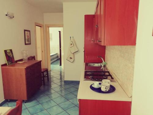 a kitchen with red cabinets and a plate on a counter at Villetta Residence Chiusurelle in Porto Cesareo