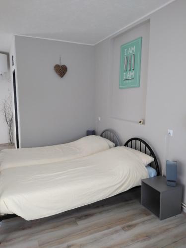 a bedroom with a white bed with a night stand at Pension Novy Den in Albrechtice