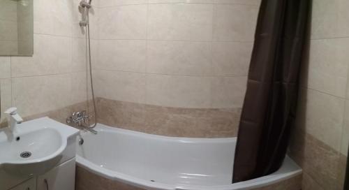 ein Bad mit einer Badewanne, einem Waschbecken und einer Dusche in der Unterkunft Comfortable apartments in Riwne