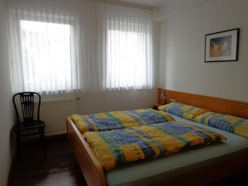 - une chambre avec deux lits, une chaise et deux fenêtres dans l'établissement Haus am Weinberg 2, à Endingen am Kaiserstuhl
