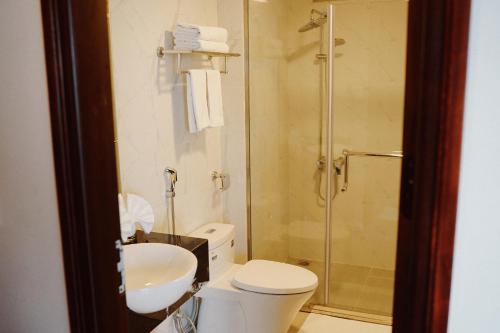 een badkamer met een douche, een toilet en een wastafel bij The Confetti hotel in Ha Long