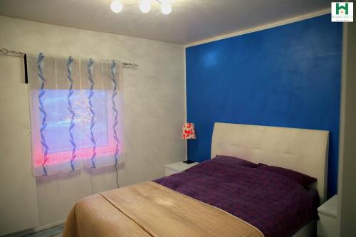 een slaapkamer met een bed en een blauwe muur bij Reydarfjordur Apartment in Reyðarfjörður