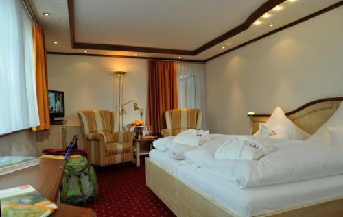 a hotel room with a large white bed and chairs at Landhotel Voss im TalVital in Saalhausen