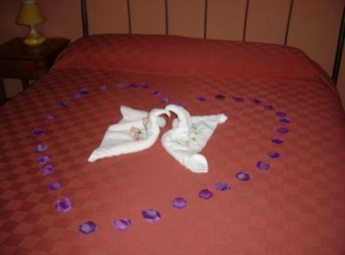 a bride and groom cut out on a bed with purple flowers at Hotel Residence Le Chiavi Di San Francesco in Trapani
