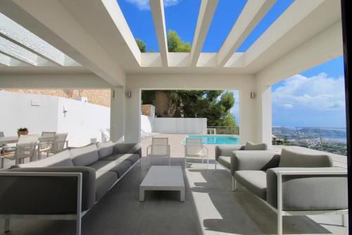 a patio with couches and a table and a pool at Villa Wivine in Moraira