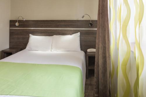 Logis Hôtel Les Voyageurs في Lezoux: غرفة نوم مع سرير مع اللوح الأمامي الخشبي
