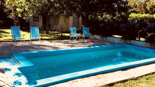 a blue swimming pool with chairs and a table at Altos de la Laguna in Chascomús